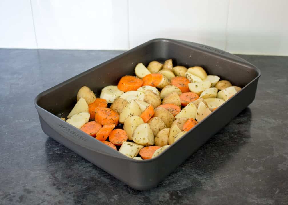 Chopped potatoes and carrots in a roasting tin